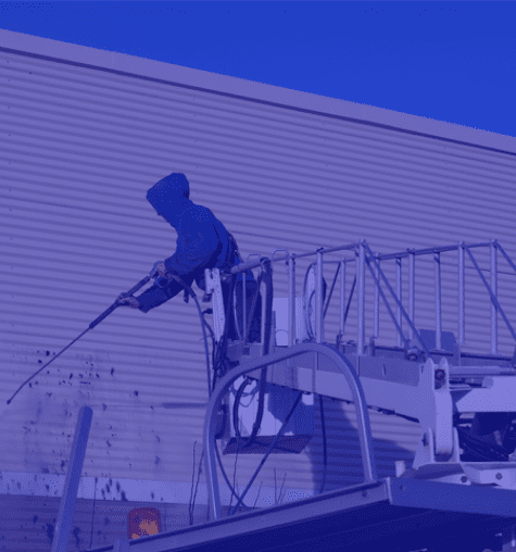 Worker using a hose to spray water on a rooftop structure.