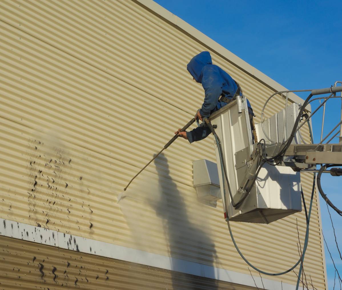 Man cleaning wall with power washer