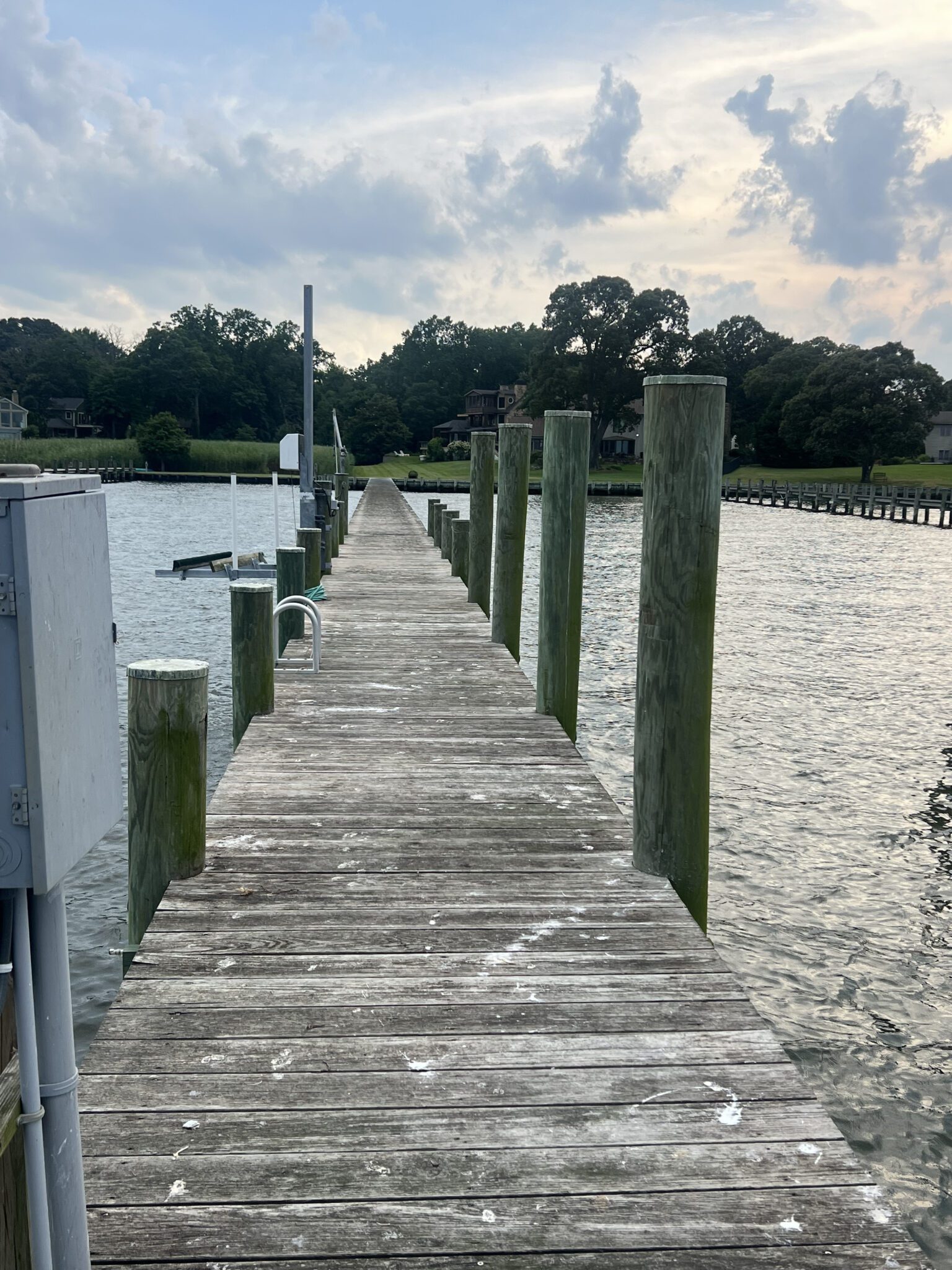 Wooden dock extending over calm water under a cloudy sky.