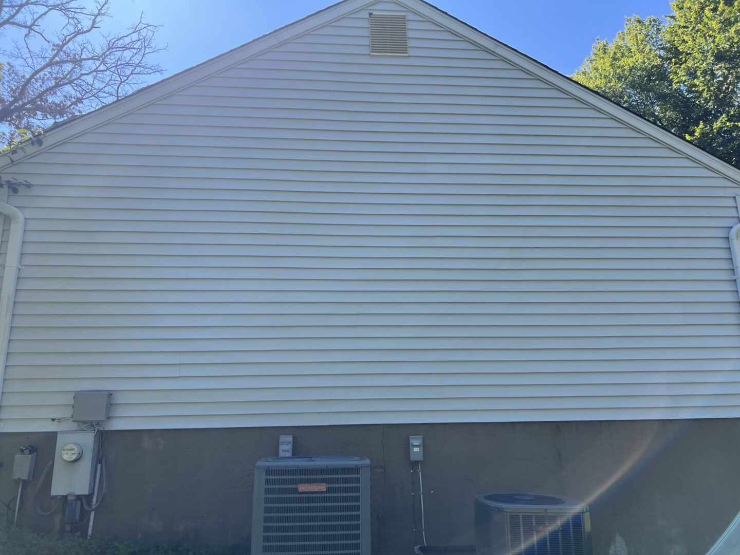 Side view of a house with a gray air conditioning unit outside.
